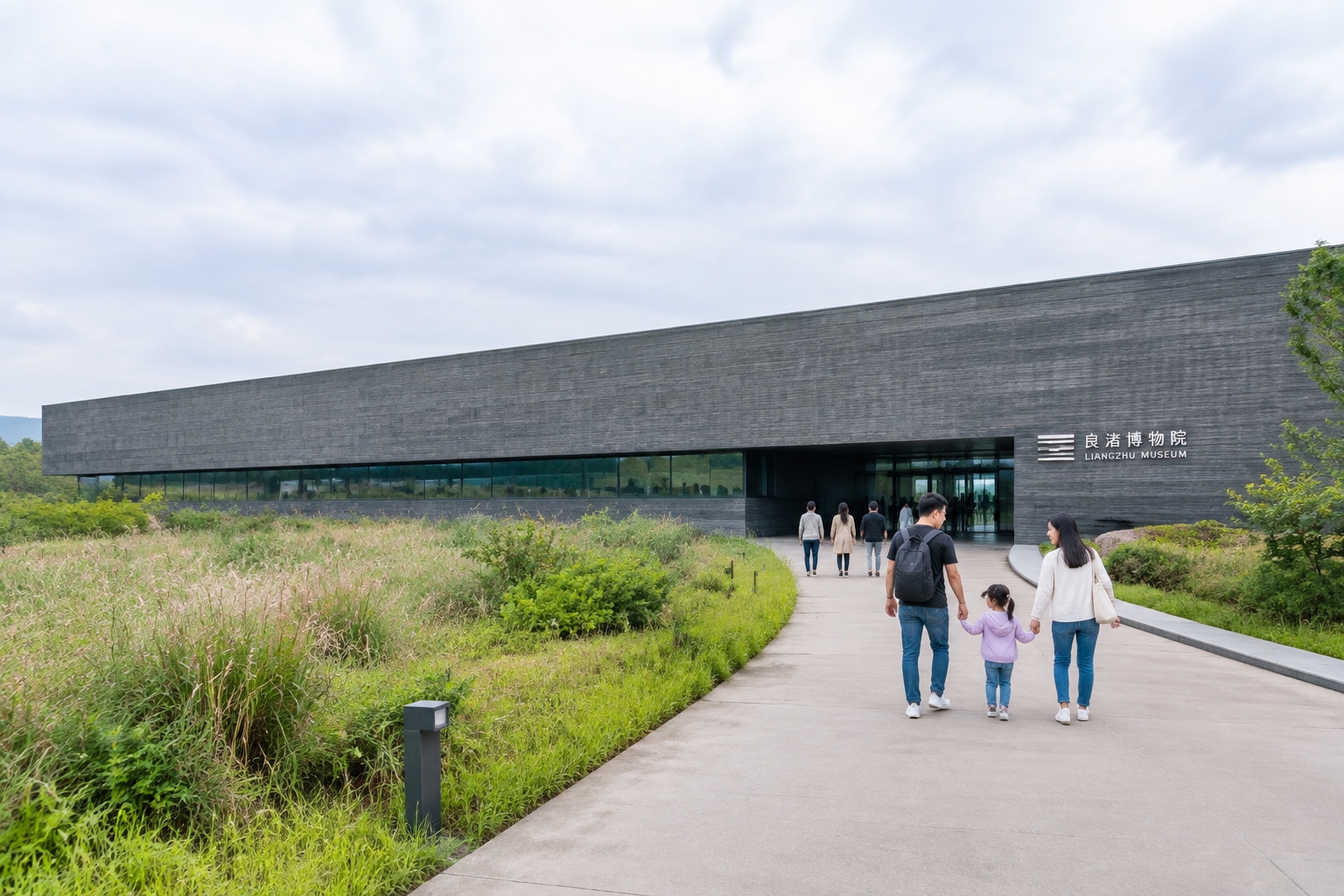 Visitors walking toward the low grey concrete Liangzhu Museum building surrounded by tall grass near Hangzhou, China